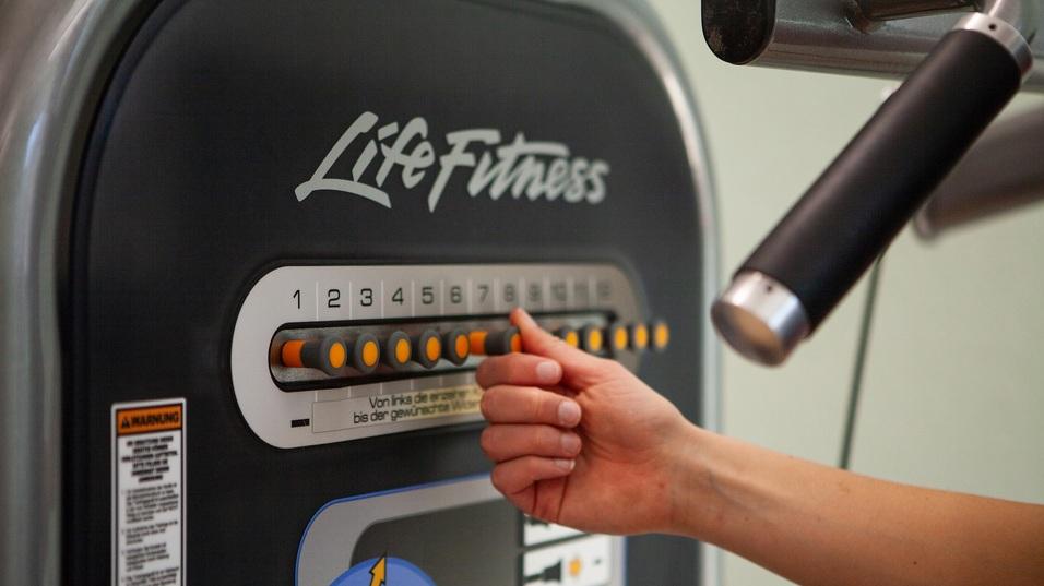 Nahaufnahme einer Hand, die einen Trainingswiderstand an einem Life Fitness-Gerät einstellt.